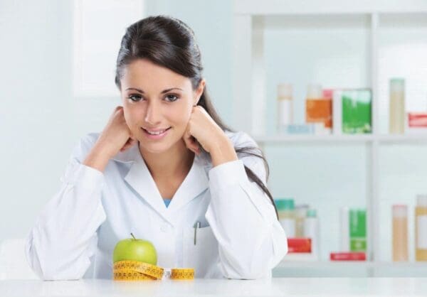 Smiling doctor, apple, measuring tape, healthy.